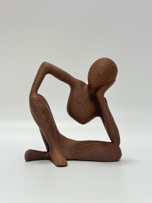 Abstract home decor figurine showing serene seated pose with natural wood-like surface