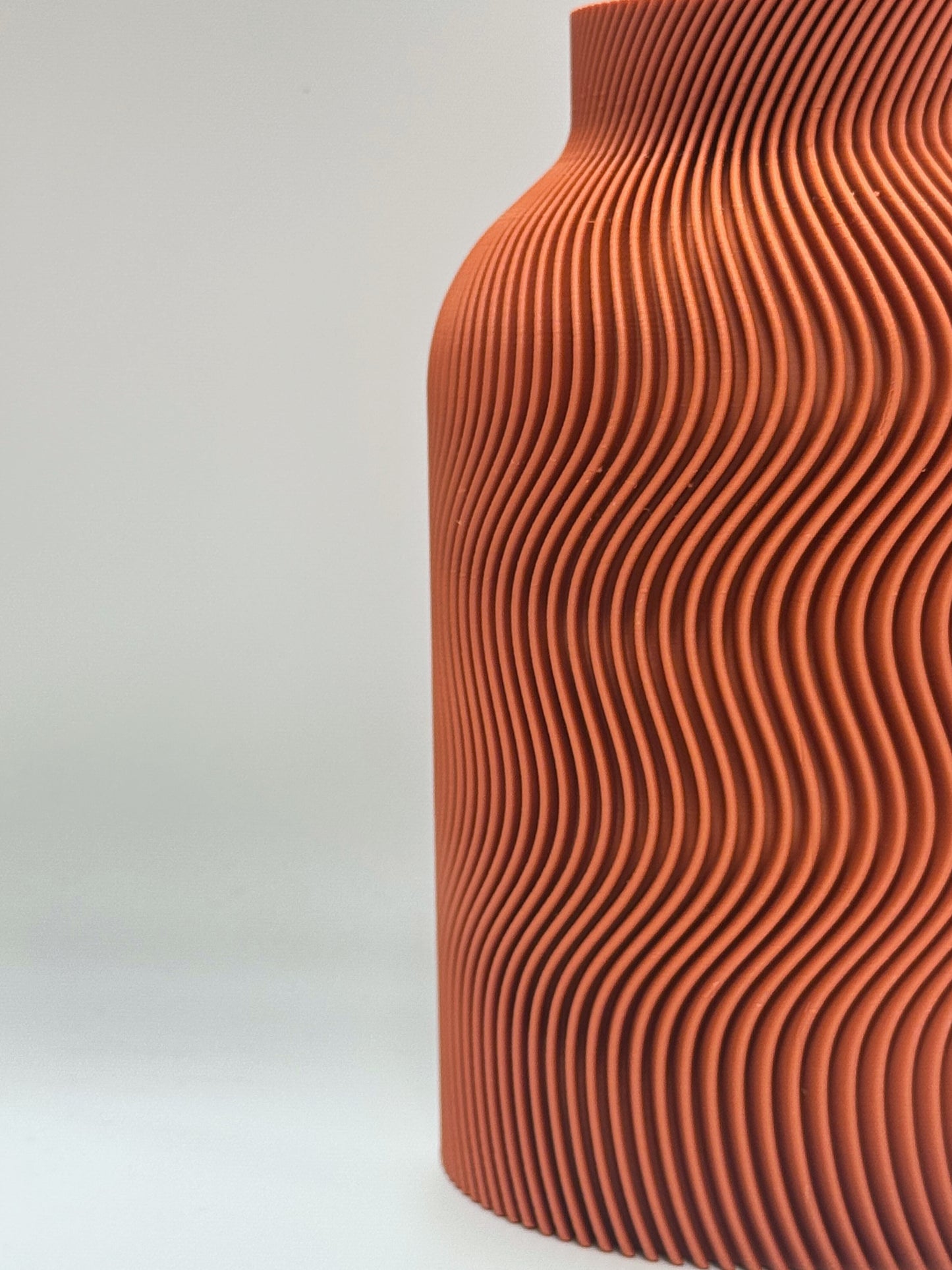 Luna Vase in Terra Cotta color, featuring elegant curved wave patterns and included glass insert